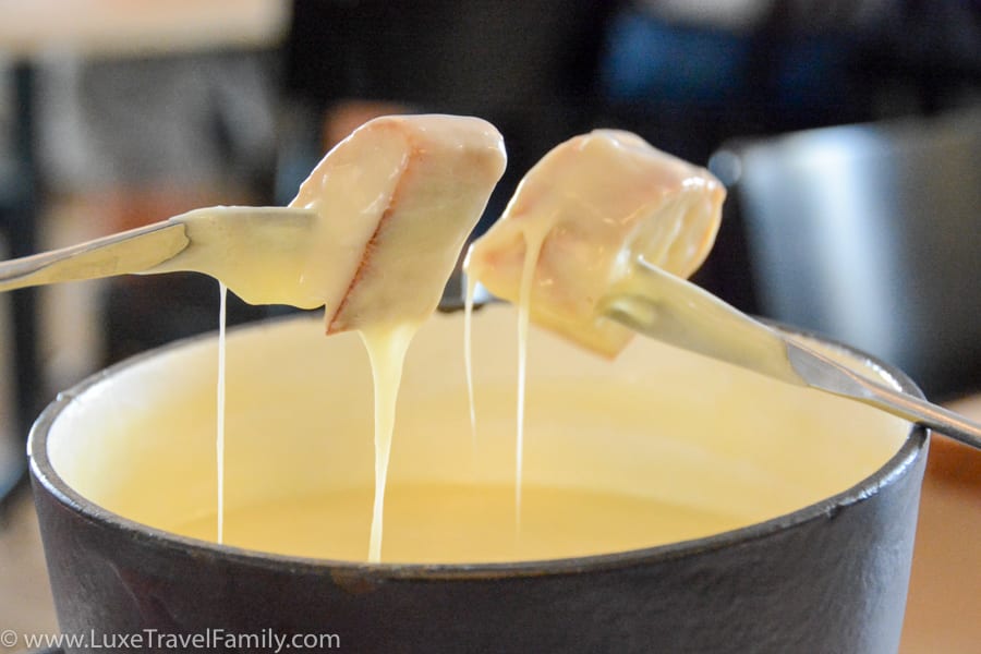 A fondue pot, two forks and bread dripping with cheese at the Swiss Pavilion restaurant, Expo 2015