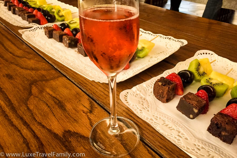 A glass of rose Codorníu cava and platters of fruit on a skewer