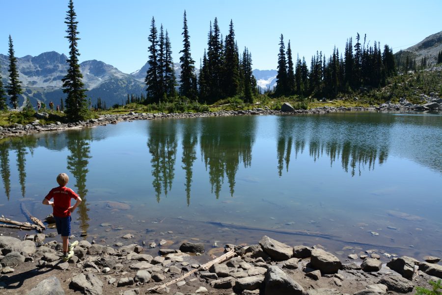 Boy lookin at clear alpine lake in Whistler
