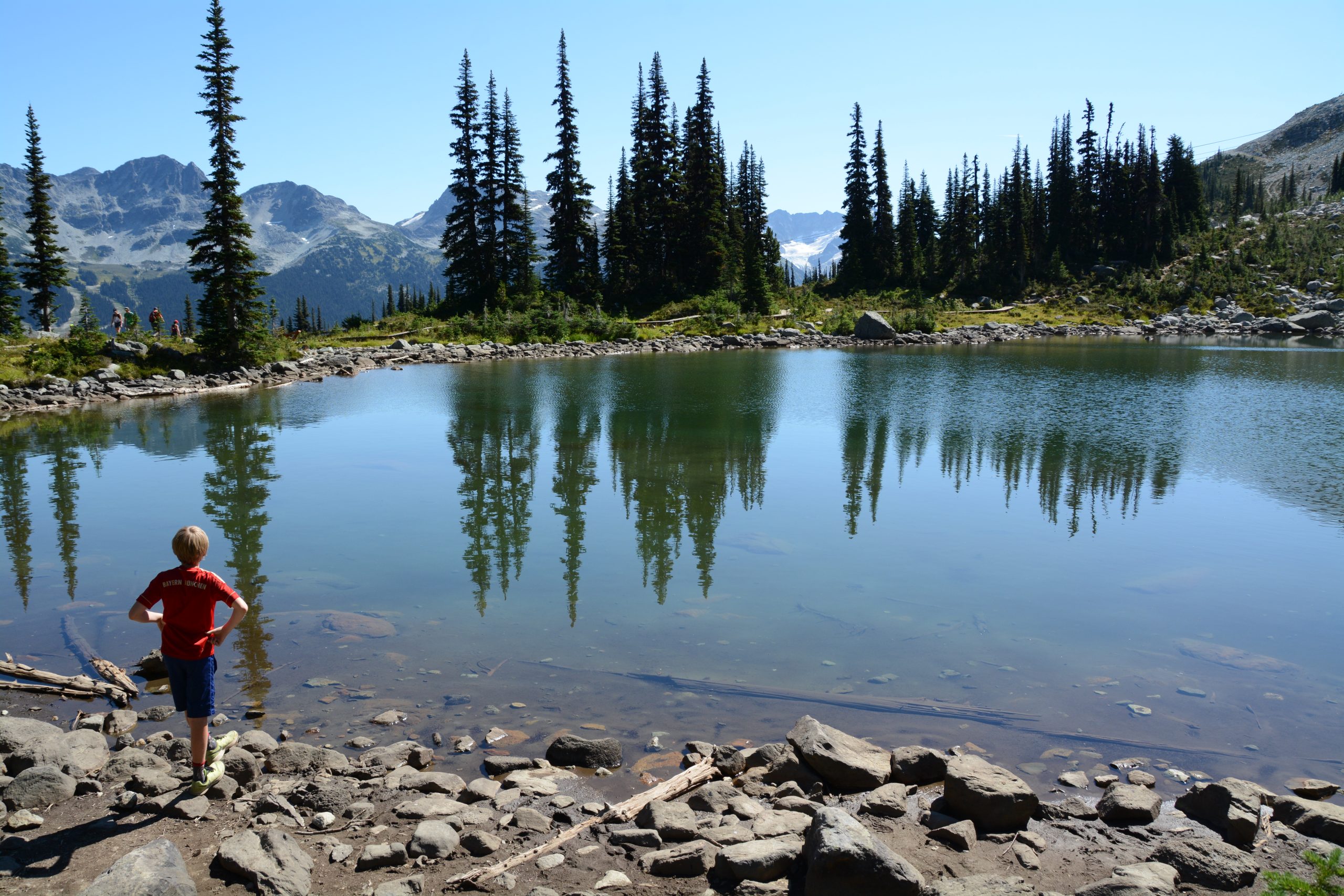 Boy lookin at clear alpine lake in Whistler