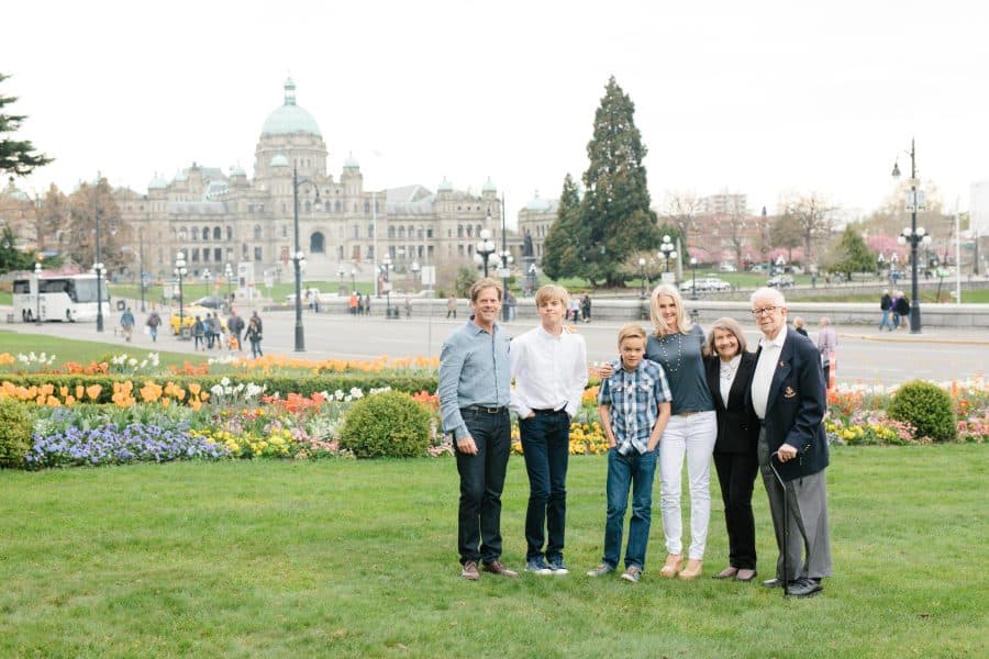 Multigenerational family on the green grass bordered by spring flowers in Victoria Bc